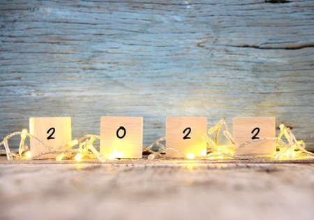 Happy New year 2022 on brown wood table and blur abstract bokeh lightの写真素材