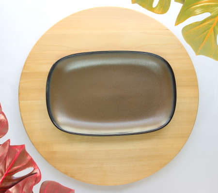 dish is placed on a round wooden table with monstera palm leaves for decoration