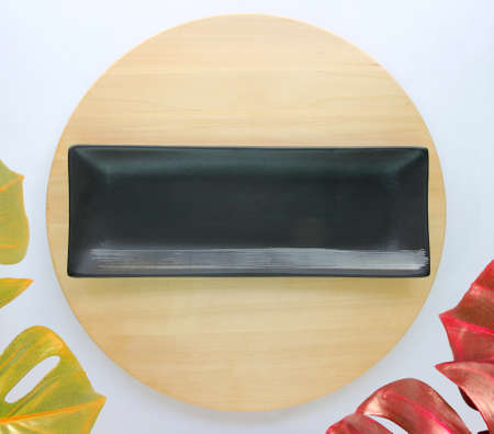 dish is placed on a round wooden table with monstera palm leaves for decoration