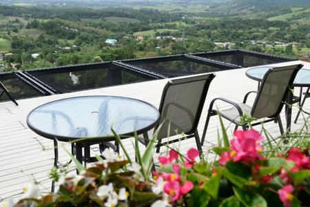 Tables and iron chairs on terrace with flower pots and beautiful landscape view