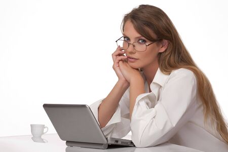 The modern, beautiful, young woman sits at a table with a personal computerの写真素材
