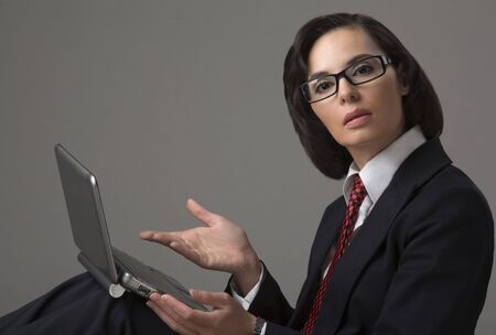 Portrait of the business woman on a grey background with the laptopの写真素材