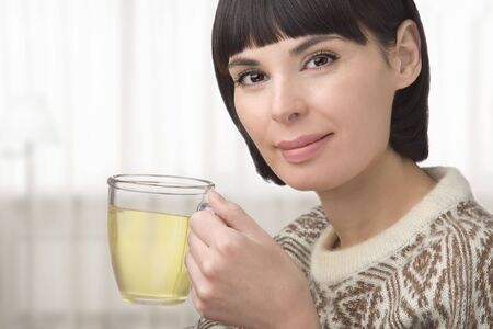 The young woman holds in hand a cup with green teaの写真素材