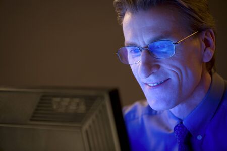 Businessman works behind the computer in the eveningの写真素材
