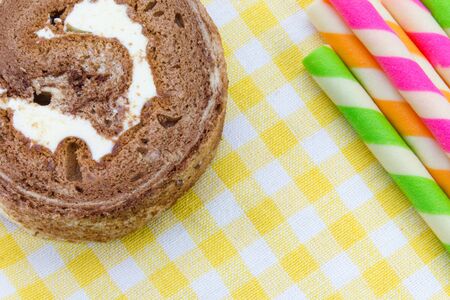 Chocolate roll and Wafer rolls on yellow tableclothの写真素材