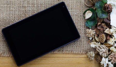 Dry flowers frame on wooden background with tablet computer (tablet pc)の写真素材
