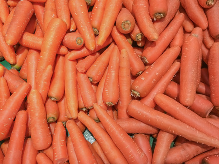 Fresh carrots piled high on a market stallの写真素材