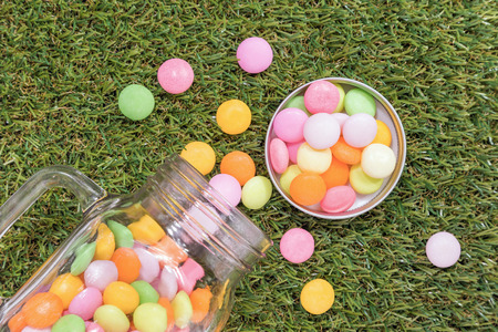 Sweet candy in glass jar over grass backgroundの写真素材