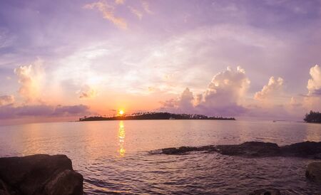 Sunset over the ocean with tropical islandの写真素材