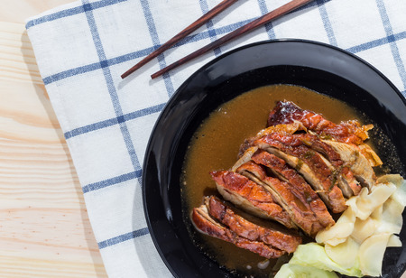 Roast duck and sauces with chopsticks over wooden tableの写真素材