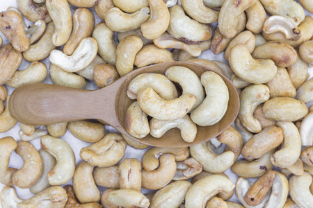 Cashews nut heap in wooden spoon top view
