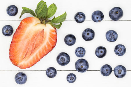 strawberry and blueberries fruits over white wooden backgroundの写真素材