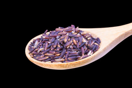 Black jasmine rice Thailand (Rice Berry) in wooden spoon over black backgroundの写真素材