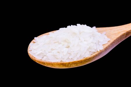 uncooked jasmine rice in wooden spoon over black background, Selective focus
