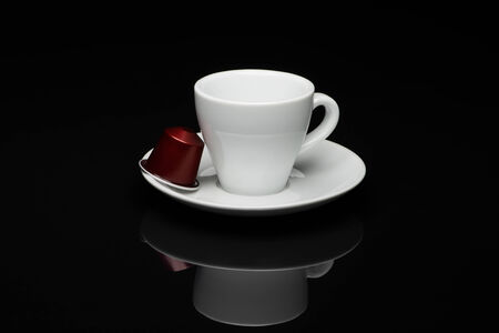 Cup of coffee with capsules on black background with reflectionのeditorial素材