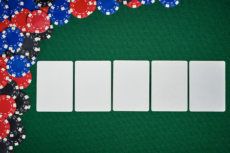 Poker chips with blank cards on green table in casino