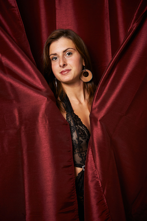 Young girl in underwear before red curtainの写真素材