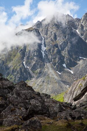 Rugged mountain peaks lie shrouded in clouds on a summer dayの写真素材
