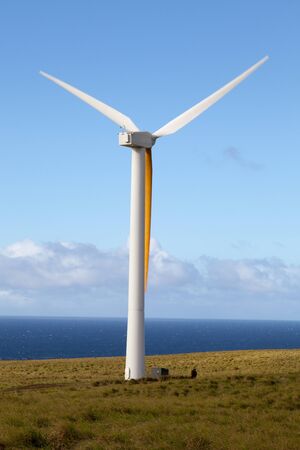 Wind generator spins in an open field overlooking Pacific Oceanの写真素材