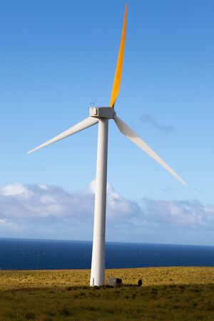 Wind generator spins in an open field overlooking Pacific Oceanの写真素材
