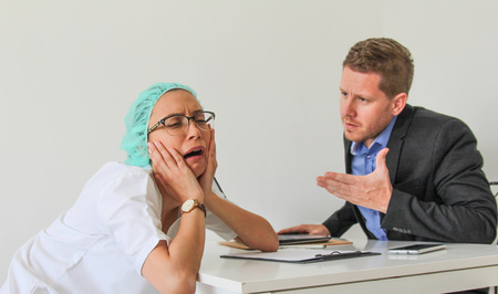 a sad nurse at a meeting with her manager in the officeの写真素材