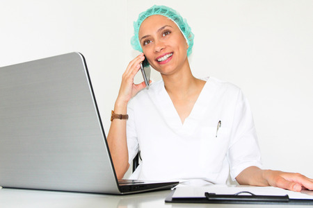 A young woman doctor With a laptop in her office talking on the phoneの写真素材