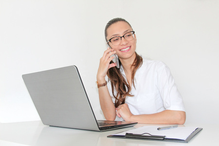 A young woman doctor With a laptop in her office talking on the phoneの写真素材