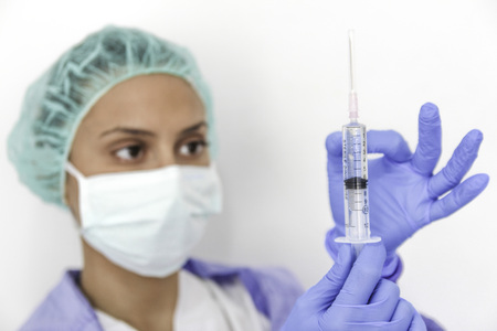 A doctor nurse with gloves holds a syringeの写真素材