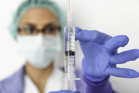 A doctor nurse with gloves holds a syringeの写真素材