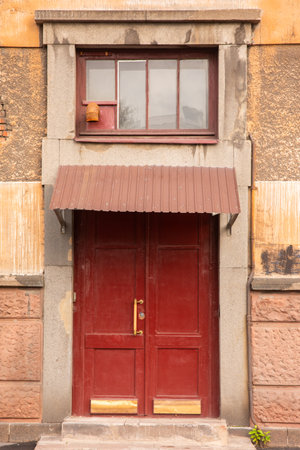 Old red wooden door with window and shutters on the wall.の写真素材