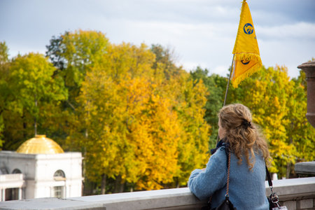 Young woman with a yellow flag on the background of the autumn park.の写真素材