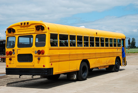Yellow school bus on a background of blue sky and white clouds.の写真素材