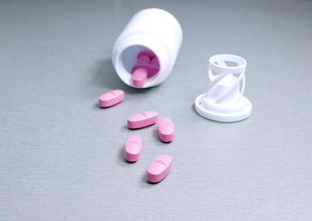 Pink pills spilling out of their containerの写真素材