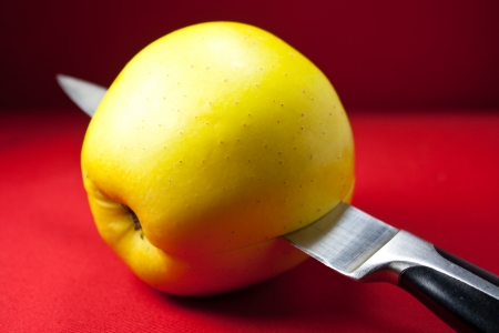 Knife slicing an apple on red backgroundの写真素材