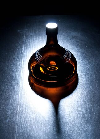 Amber bottle in green spotlight on the floorの写真素材