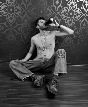 Skinny man on the floor drinkingの写真素材
