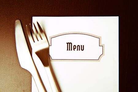 Silverware and a menu on a restaurant tableの写真素材