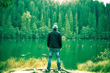 Man standing looking away onto the lakeの写真素材