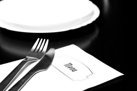 Silverware and a menu on a restaurant tableの写真素材