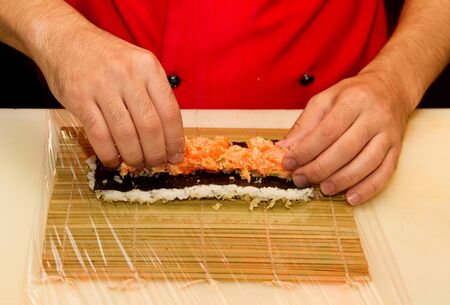 Chef preparing a roll of salmon sushiの写真素材