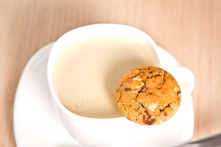 Homemade cookie on the rim of a cup of coffeeの写真素材