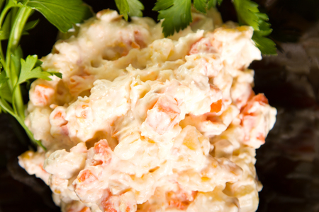 Potato salad in a black bowl with decorative parsleyの写真素材