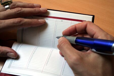 Female hand holding a pen to fill the Agenda