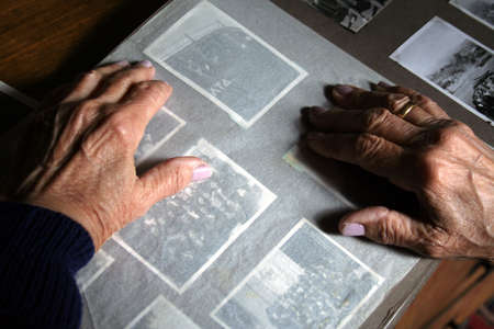 An old woman's hands on an old photo albumの写真素材