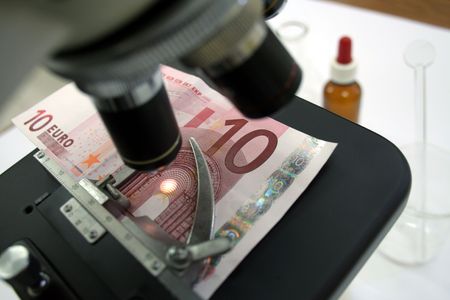 Checking for fake euro banknote using a microscopeの写真素材