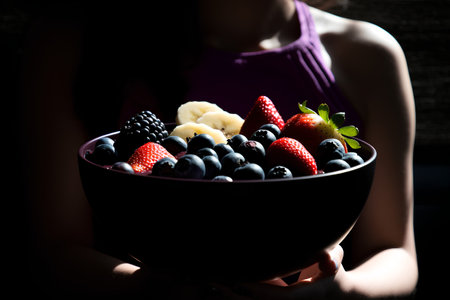 Woman holding bowl with fresh berries, selective focus, toned imageの素材