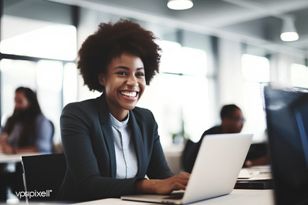 Smiling african american businesswoman working on laptop in officeの素材