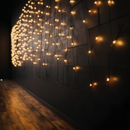 Christmas garland lights on a black wall with a wooden floor.の素材