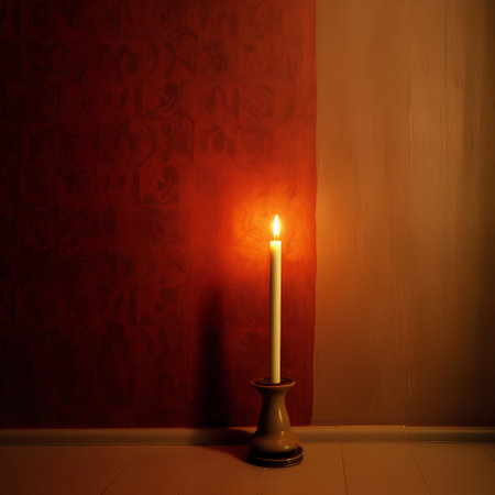 Burning candle in a candlestick on a red wall backgroundの素材