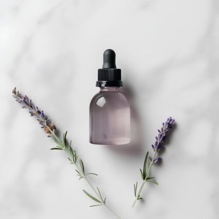 Bottle of essential oil with lavender flowers on white marble backgroundの素材